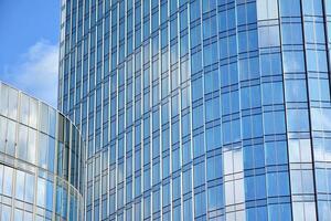 Glass building with transparent facade of the building and blue sky. Structural glass wall reflecting blue sky. Abstract modern architecture fragment. Contemporary architectural background. photo