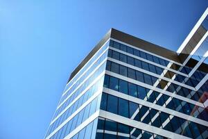Glass building with transparent facade of the building and blue sky. Structural glass wall reflecting blue sky. Abstract modern architecture fragment. Contemporary architectural background. photo