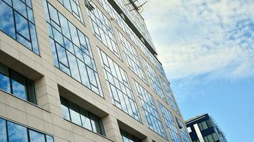 Glass building with transparent facade of the building and blue sky. Structural glass wall reflecting blue sky. Abstract modern architecture fragment. Contemporary architectural background. photo