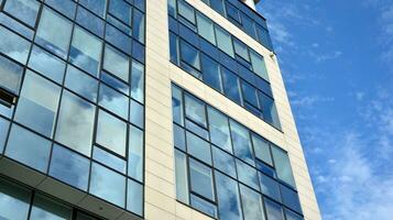 Glass building with transparent facade of the building and blue sky. Structural glass wall reflecting blue sky. Abstract modern architecture fragment. Contemporary architectural background. photo
