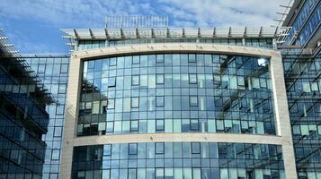 Glass building with transparent facade of the building and blue sky. Structural glass wall reflecting blue sky. Abstract modern architecture fragment. Contemporary architectural background. photo