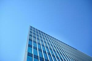 Glass building with transparent facade of the building and blue sky. Structural glass wall reflecting blue sky. Abstract modern architecture fragment. Contemporary architectural background. photo