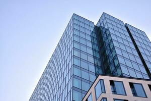 Glass building with transparent facade of the building and blue sky. Structural glass wall reflecting blue sky. Abstract modern architecture fragment. Contemporary architectural background. photo