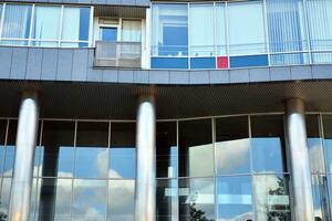 Glass building with transparent facade of the building and blue sky. Structural glass wall reflecting blue sky. Abstract modern architecture fragment. Contemporary architectural background. photo