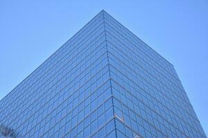 Glass building with transparent facade of the building and blue sky. Structural glass wall reflecting blue sky. Abstract modern architecture fragment. Contemporary architectural background. photo