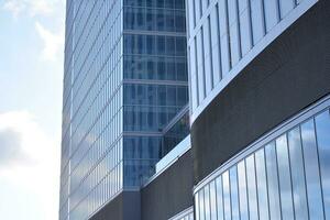 Glass building with transparent facade of the building and blue sky. Structural glass wall reflecting blue sky. Abstract modern architecture fragment. Contemporary architectural background. photo