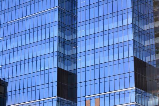 Glass building with transparent facade of the building and blue sky. Structural glass wall reflecting blue sky. Abstract modern architecture fragment. Contemporary architectural background. photo