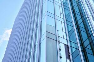 Glass building with transparent facade of the building and blue sky. Structural glass wall reflecting blue sky. Abstract modern architecture fragment. Contemporary architectural background. photo