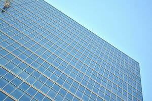 Glass building with transparent facade of the building and blue sky. Structural glass wall reflecting blue sky. Abstract modern architecture fragment. Contemporary architectural background. photo