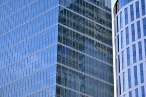 Glass building with transparent facade of the building and blue sky. Structural glass wall reflecting blue sky. Abstract modern architecture fragment. Contemporary architectural background. photo