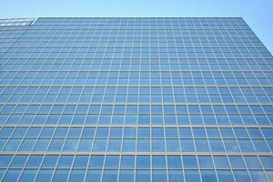 Glass building with transparent facade of the building and blue sky. Structural glass wall reflecting blue sky. Abstract modern architecture fragment. Contemporary architectural background. photo