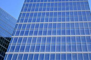 Glass building with transparent facade of the building and blue sky. Structural glass wall reflecting blue sky. Abstract modern architecture fragment. Contemporary architectural background. photo