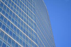 Glass building with transparent facade of the building and blue sky. Structural glass wall reflecting blue sky. Abstract modern architecture fragment. Contemporary architectural background. photo