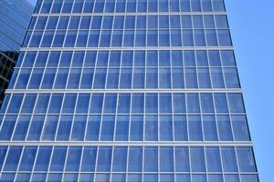 Glass building with transparent facade of the building and blue sky. Structural glass wall reflecting blue sky. Abstract modern architecture fragment. Contemporary architectural background. photo