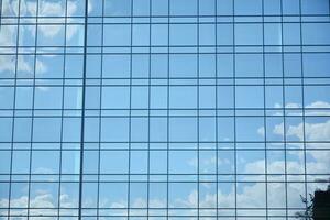 Glass building with transparent facade of the building and blue sky. Structural glass wall reflecting blue sky. Abstract modern architecture fragment. Contemporary architectural background. photo