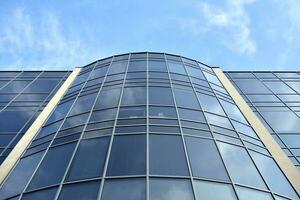 Glass building with transparent facade of the building and blue sky. Structural glass wall reflecting blue sky. Abstract modern architecture fragment. Contemporary architectural background. photo