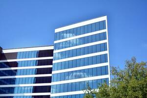 Glass building with transparent facade of the building and blue sky. Structural glass wall reflecting blue sky. Abstract modern architecture fragment. Contemporary architectural background. photo