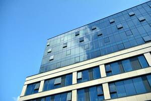 Glass building with transparent facade of the building and blue sky. Structural glass wall reflecting blue sky. Abstract modern architecture fragment. Contemporary architectural background. photo