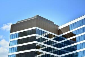 Glass building with transparent facade of the building and blue sky. Structural glass wall reflecting blue sky. Abstract modern architecture fragment. Contemporary architectural background. photo