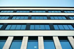 Glass building with transparent facade of the building and blue sky. Structural glass wall reflecting blue sky. Abstract modern architecture fragment. Contemporary architectural background. photo