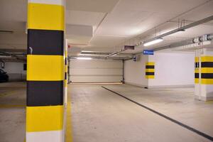 Departure from the underground garage with white gate. Interior pillars painted yellow. photo