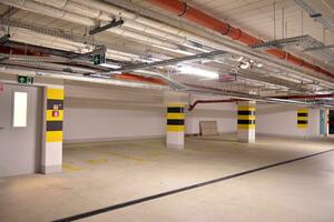 Departure from the underground garage with white gate. Interior pillars painted yellow. photo