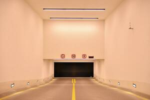 Departure from the underground garage with white gate. Interior pillars painted yellow. photo