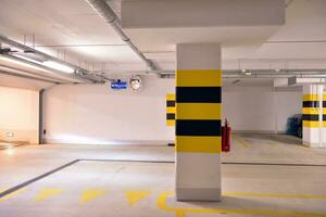 Departure from the underground garage with white gate. Interior pillars painted yellow. photo