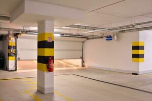 Departure from the underground garage with white gate. Interior pillars painted yellow. photo