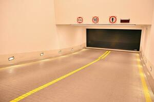 Departure from the underground garage with white gate. Interior pillars painted yellow. photo