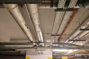 Sanitary system pipes and electrical cables installed under flat slab reinforced concrete structure in building. photo