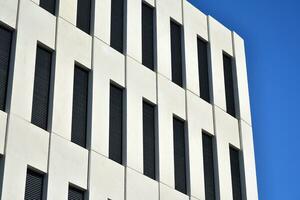 Modern office building detail. Perspective view of geometric angular concrete windows on the facade of a modernist brutalist style building. photo