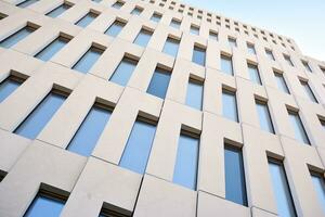 Modern office building detail. Perspective view of geometric angular concrete windows on the facade of a modernist brutalist style building. photo