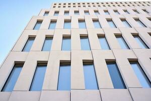 Modern office building detail. Perspective view of geometric angular concrete windows on the facade of a modernist brutalist style building. photo