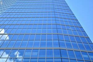 moderno oficina edificio con vaso fachada en un claro cielo antecedentes. transparente vaso pared de oficina edificio. foto