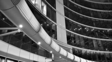 Amazing night cityscape. Office building at night, building facade with glass and lights. View with illuminated modern skyscraper. Scenic glowing windows of skyscrapers at evening. Black and white. photo