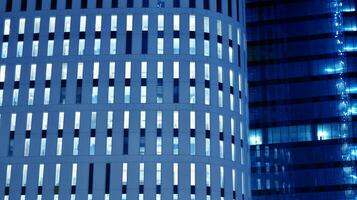 Pattern of office buildings windows illuminated at night. Glass architecture ,corporate building at night - business concept. Blue graphic filter. photo
