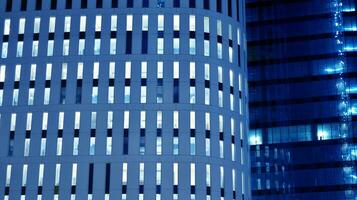 Pattern of office buildings windows illuminated at night. Glass architecture ,corporate building at night - business concept. Blue graphic filter. photo