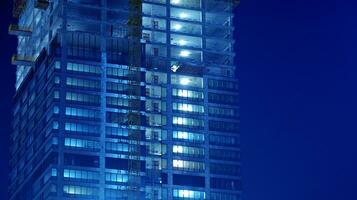 Pattern of office buildings windows illuminated at night. Glass architecture ,corporate building at night - business concept. Blue graphic filter. photo