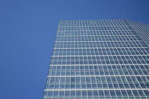 moderno oficina edificio con vaso fachada en un claro cielo antecedentes. transparente vaso pared de oficina edificio. foto