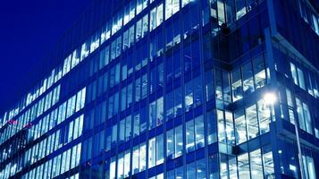 Pattern of office buildings windows illuminated at night. Glass architecture ,corporate building at night - business concept. Blue graphic filter. photo