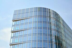 moderno oficina edificio con vaso fachada en un claro cielo antecedentes. transparente vaso pared de oficina edificio. foto