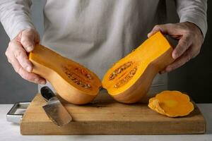 Man cutting pumpkin on a wooden cutting board. Selective focus. photo