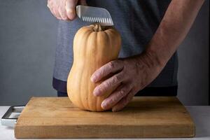 Man cutting pumpkin on a wooden cutting board. Selective focus. photo