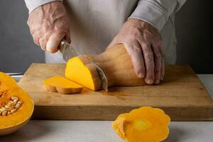 Man cutting pumpkin on a wooden cutting board. Selective focus. photo