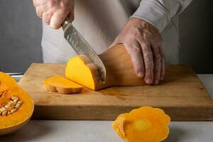 Man cutting pumpkin on a wooden cutting board. Selective focus. photo