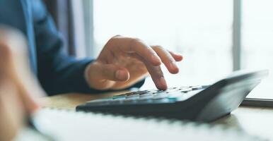 Accountant using calculator with financial documents on desk office. photo