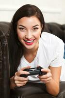 Woman gamer lies on brown leather sofa and plays a video game photo