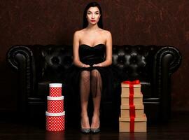 Pretty woman sittin on leather sofa between stacks of presents photo