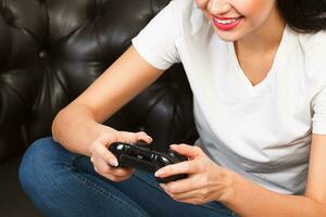 Woman gamer sitting on brown leather sofa and playing a video game photo